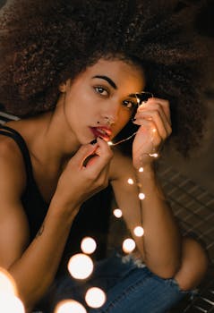 这幅令人惊叹的黑人女性肖像画，用发光的串灯摆出姿势，营造出温暖而艺术的氛围