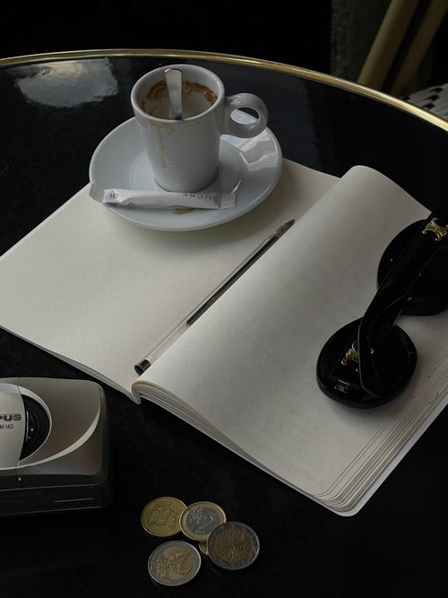 Free Overhead view of a café table with coffee, notebook, coins, and camera. Perfect for lifestyle themes. Stock Photo