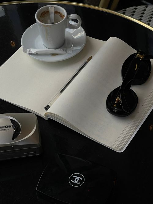 Free Elegant setup with coffee, notebook, and sunglasses on a café table. Stock Photo