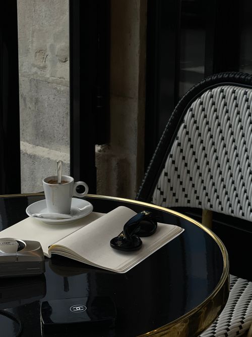 Free Elegant café table setting featuring coffee, notebook, and sunglasses for a stylish ambiance. Stock Photo
