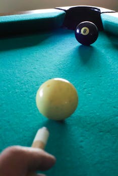 Focused view of player aiming at eight ball on a pool table.