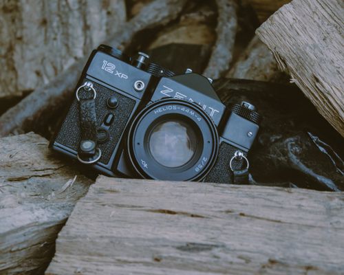 Free Close-up of a vintage Zenit camera resting on firewood, evoking nostalgia. Stock Photo