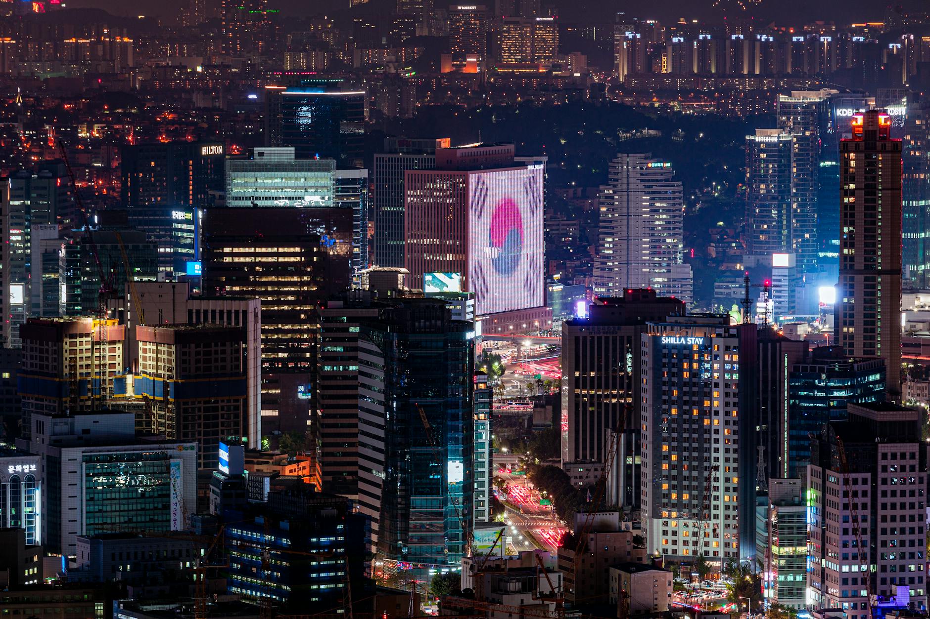 Vibrant night skyline of Seoul featuring illuminated skyscrapers and urban landscape.