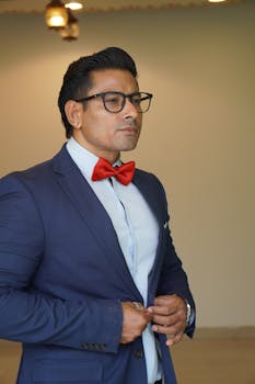 Elegant portrait of a man wearing a blue suit and red bow tie indoors.