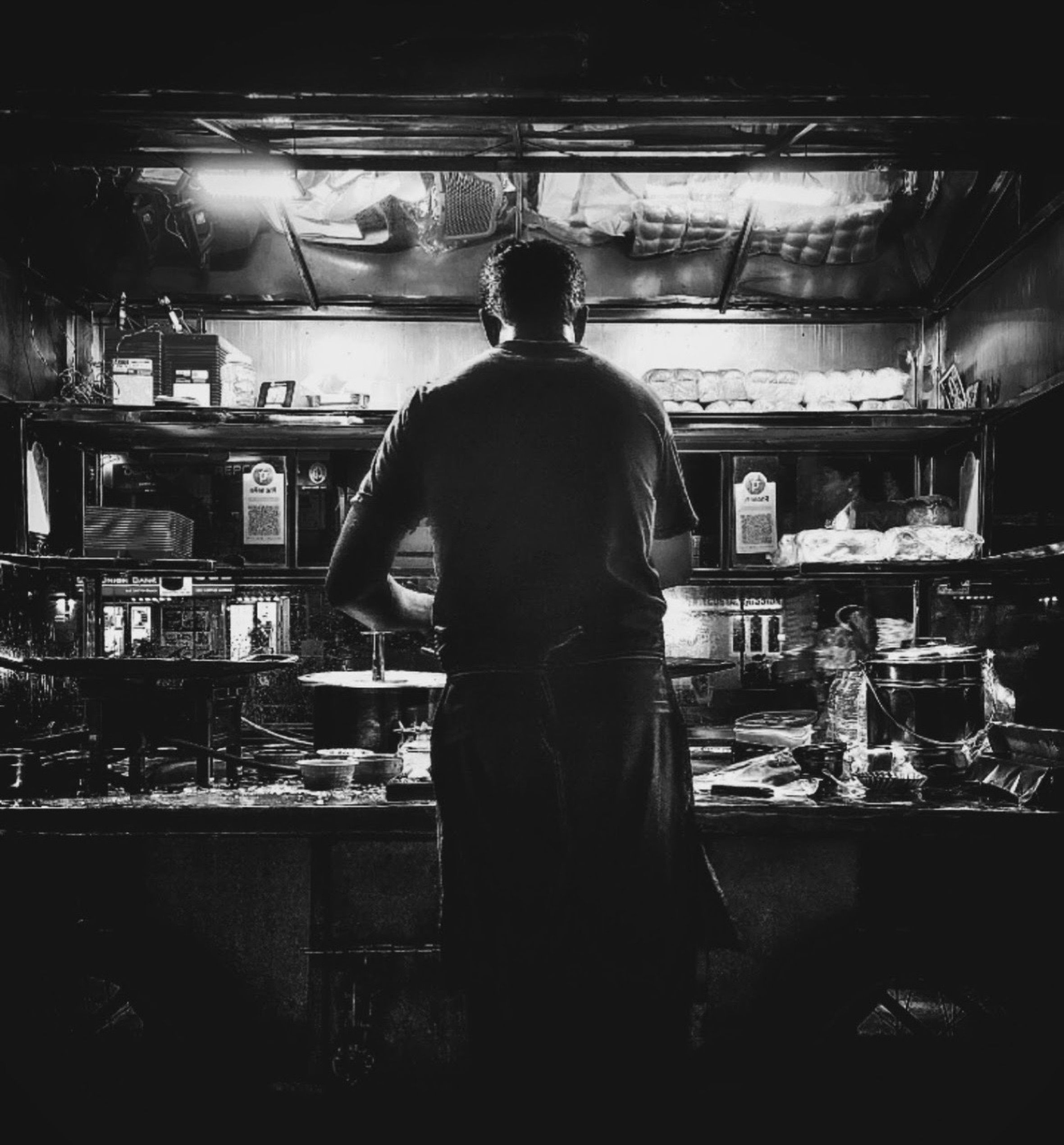 Black and white scene of a street vendor preparing food at night, capturing urban nightlife.