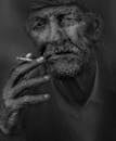 这幅引人注目的黑白肖像描绘了一位吸烟的老人，凸显了他面部的皱纹