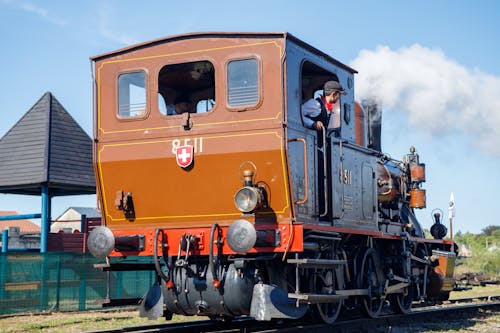 Young Men in Retro Costumes Driving a Steam Locomotive 