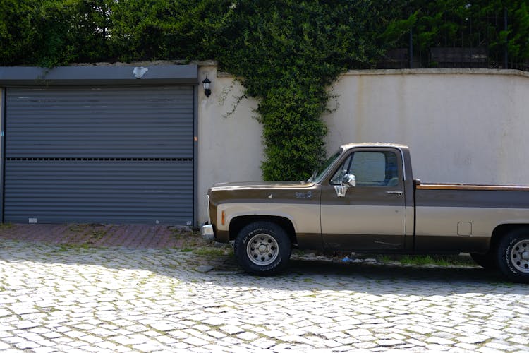 Brown Vintage Pickup Truck Parked By A Garage