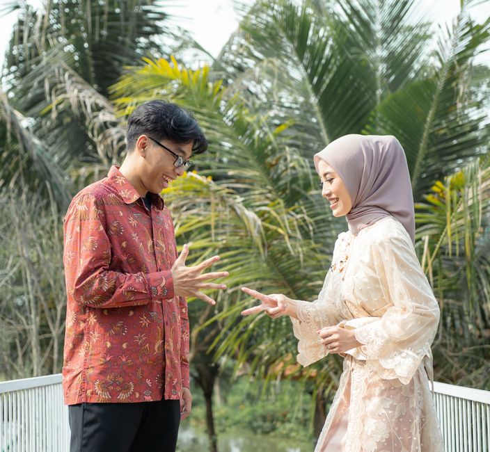 Smiling couple enjoying a friendly rock-paper-scissors game outdoors.
