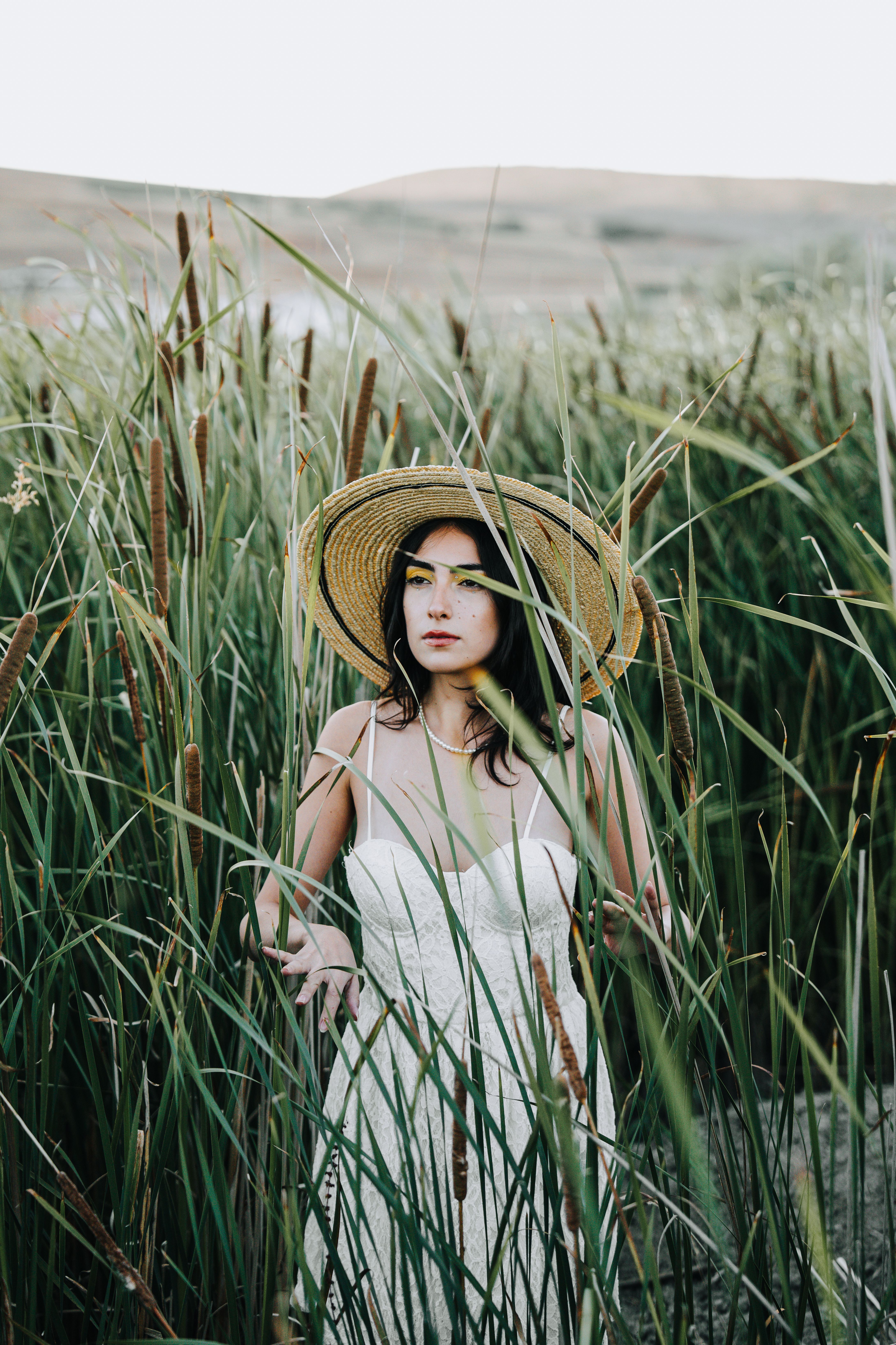 Woman in a Dress and a Hat Standing in Tall Grass · Free Stock Photo