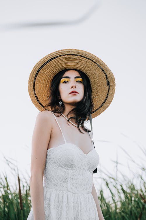 Model in a White Lace Summer Dress with Spaghetti Straps and a Straw Hat