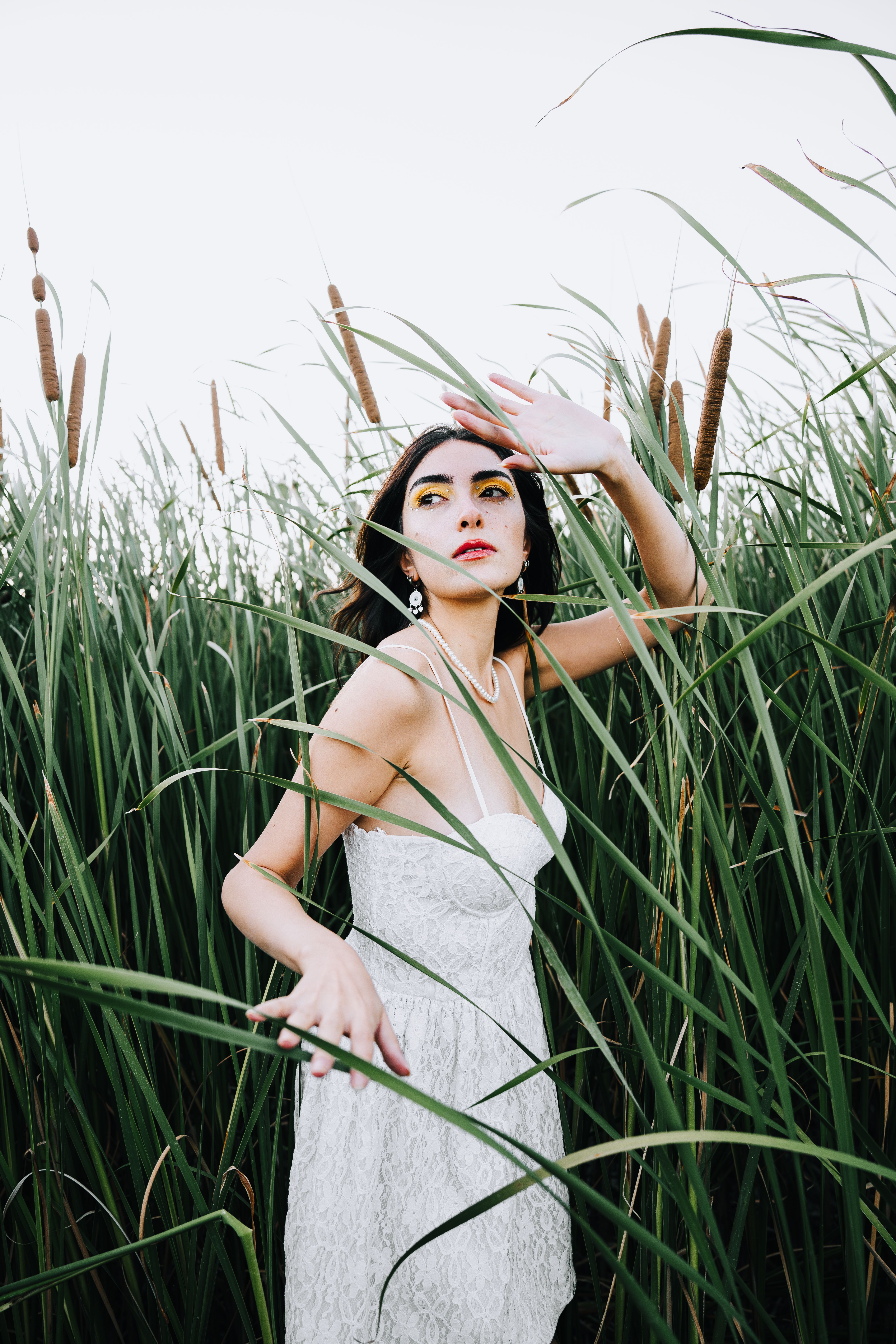 Model in a White Lace Dress Walking Through Tall Rushes · Free Stock Photo