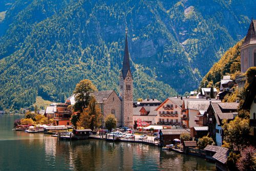 Free Picturesque view of Hallstatt, Austria with a prominent church by the waterfront, surrounded by mountains. Stock Photo