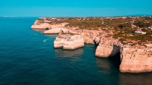 Free Scenic aerial view of the Algarve coastline with rugged cliffs and calm blue sea. Stock Photo