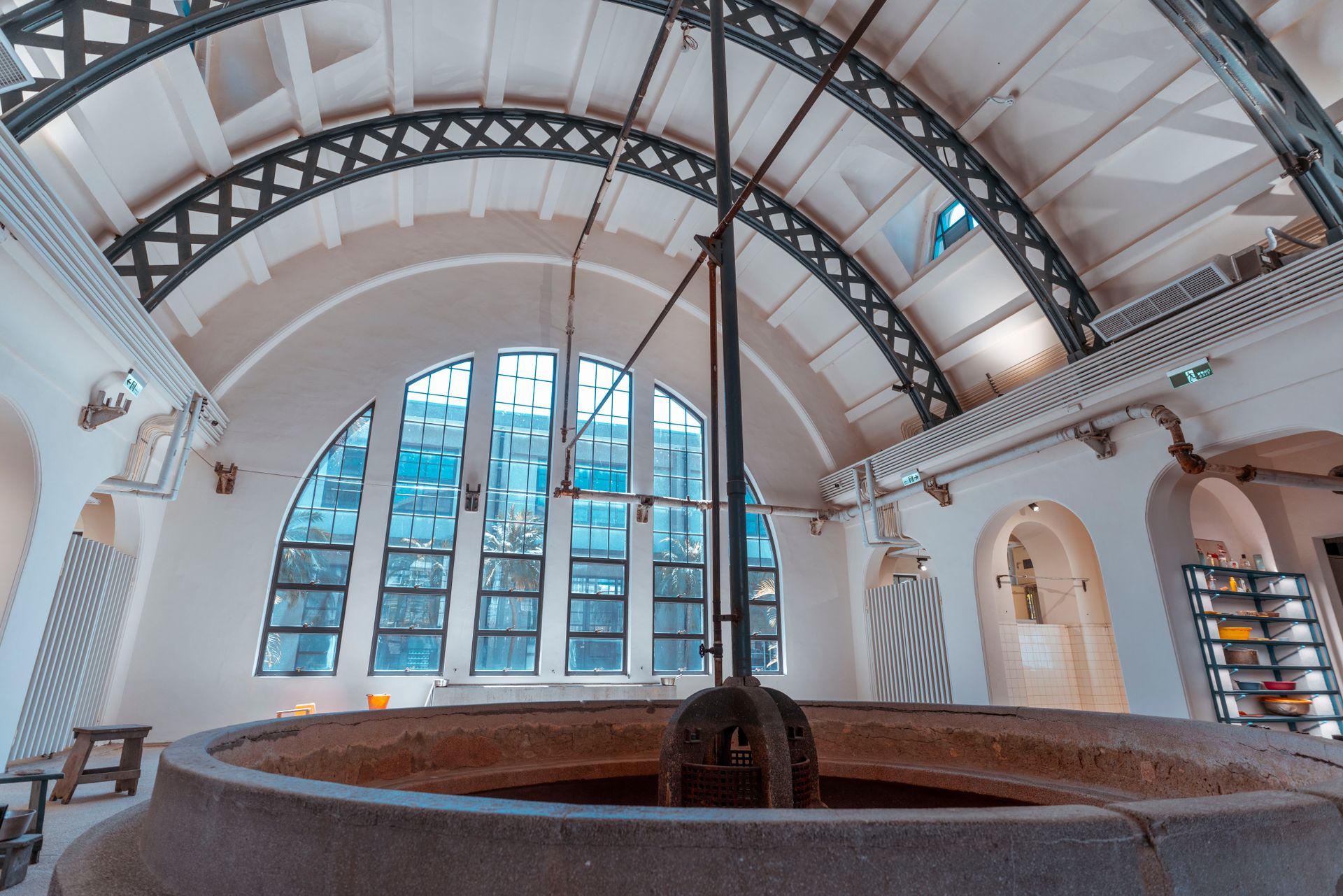 Interior of an industrial bathhouse featuring a large arched roof and architectural details.