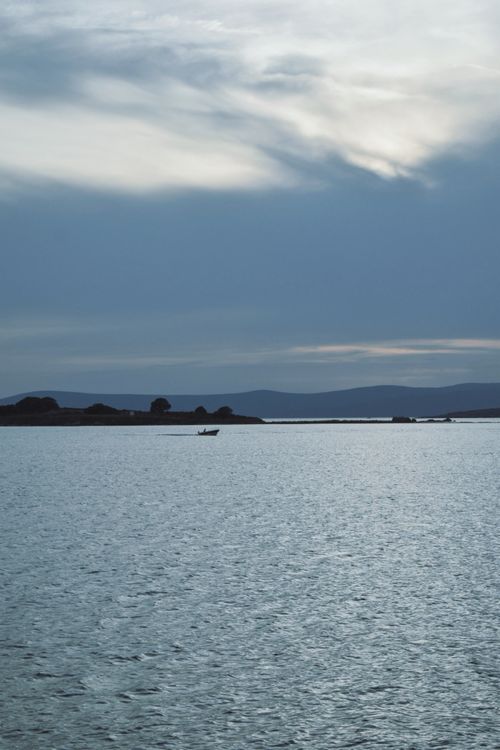 Free Calm bay with a silhouette of a boat at twilight, capturing a serene and tranquil mood. Stock Photo