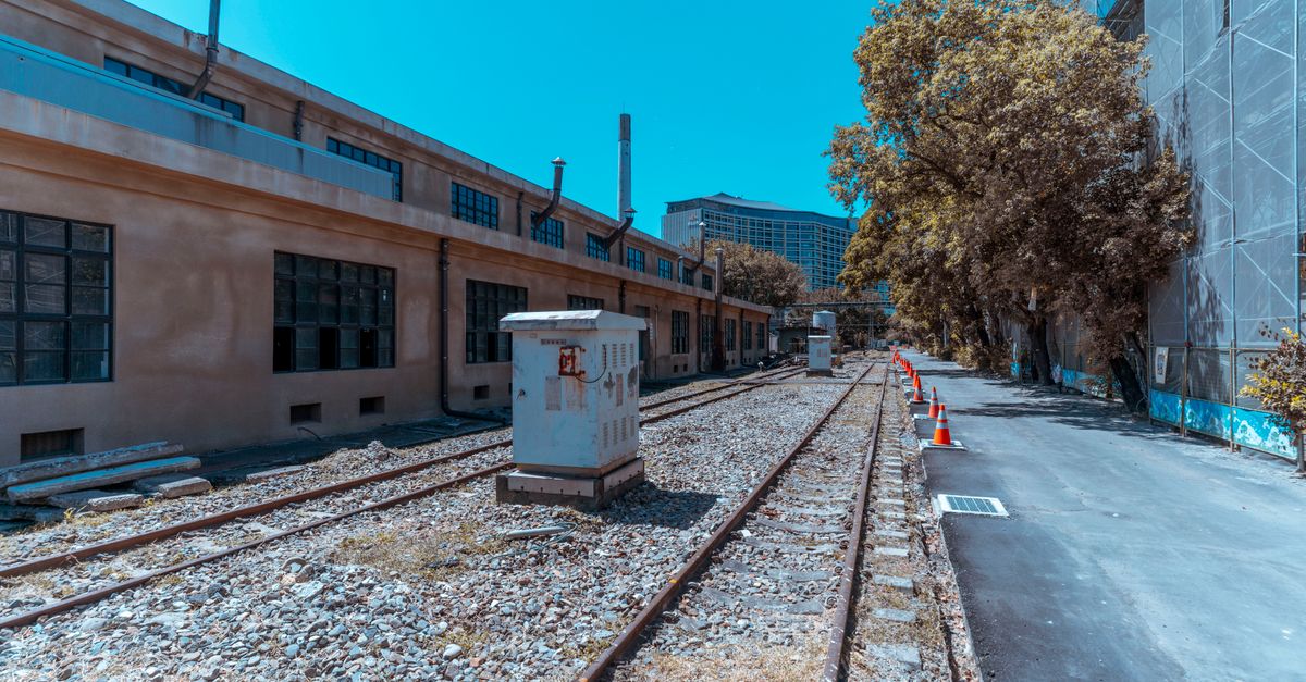 An industrial urban scene with deserted railroad tracks and buildings, exhibiting a vintage feel.