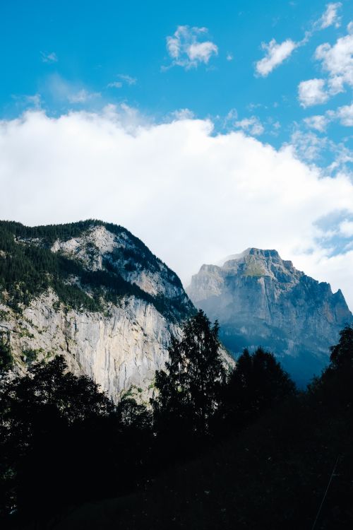 Free Scenic view of rugged mountain peaks under a bright blue sky with scattered clouds. Stock Photo