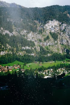 A picturesque alpine village nestled in a lush green valley surrounded by rocky cliffs.
