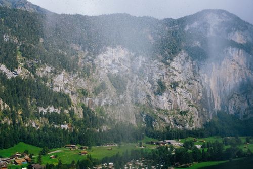 Free Breathtaking view of a village surrounded by towering cliffs and lush greenery. Stock Photo