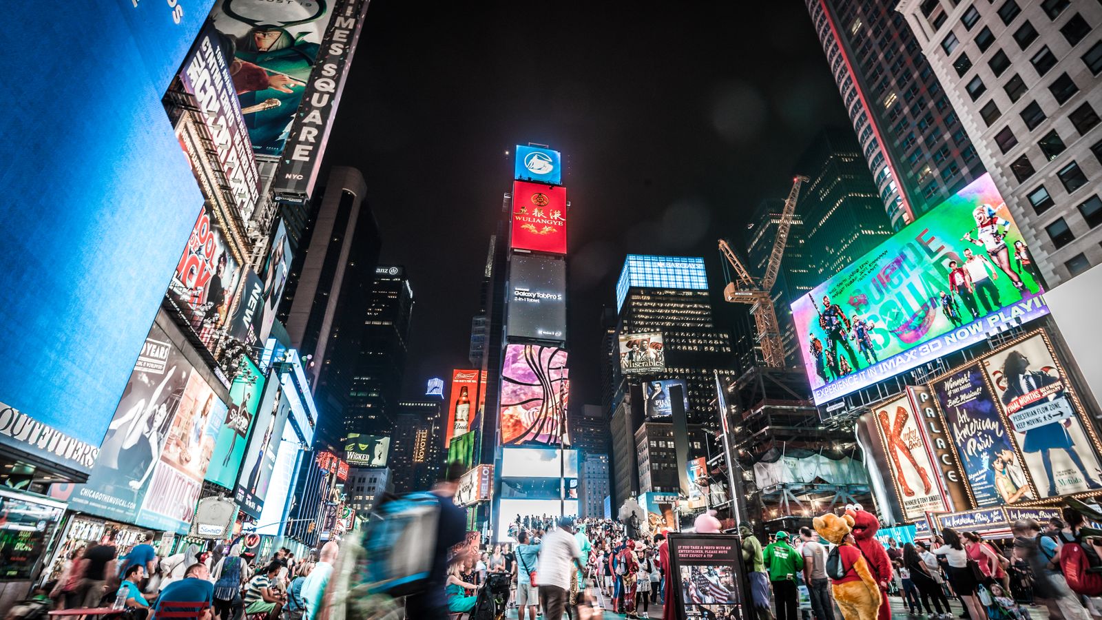 Times Square illuminated at night with bustling crowds and bright billboards in New York City.
