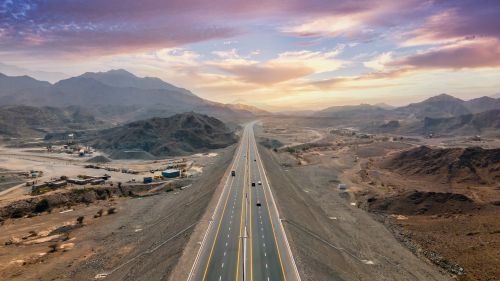 Free A breathtaking view of a desert highway with mountains in Dubai at sunset. Stock Photo
