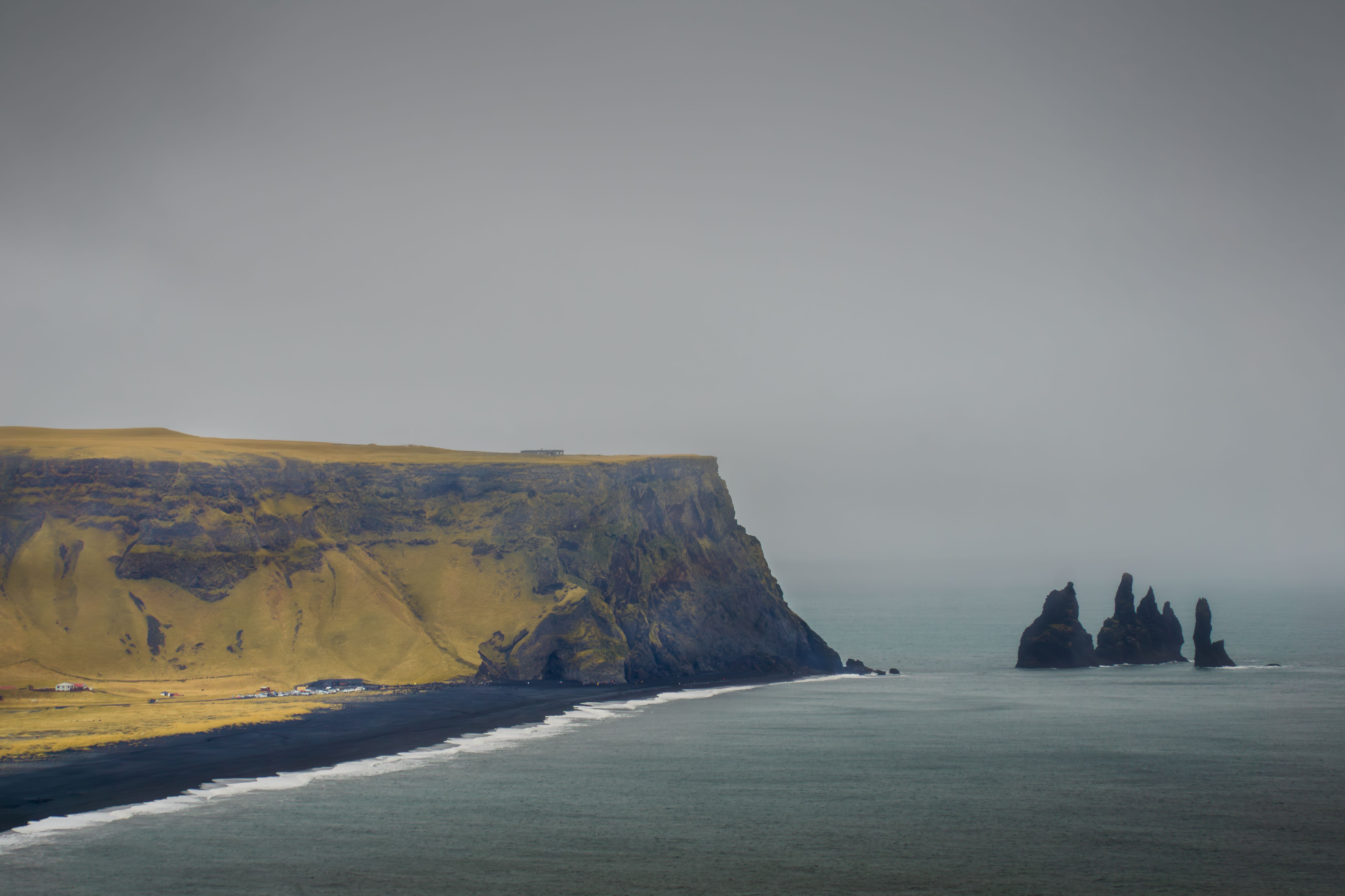 Gloomy coastal scene with majestic cliffs and iconic rock formations at Reynisfjara Beach, Iceland.