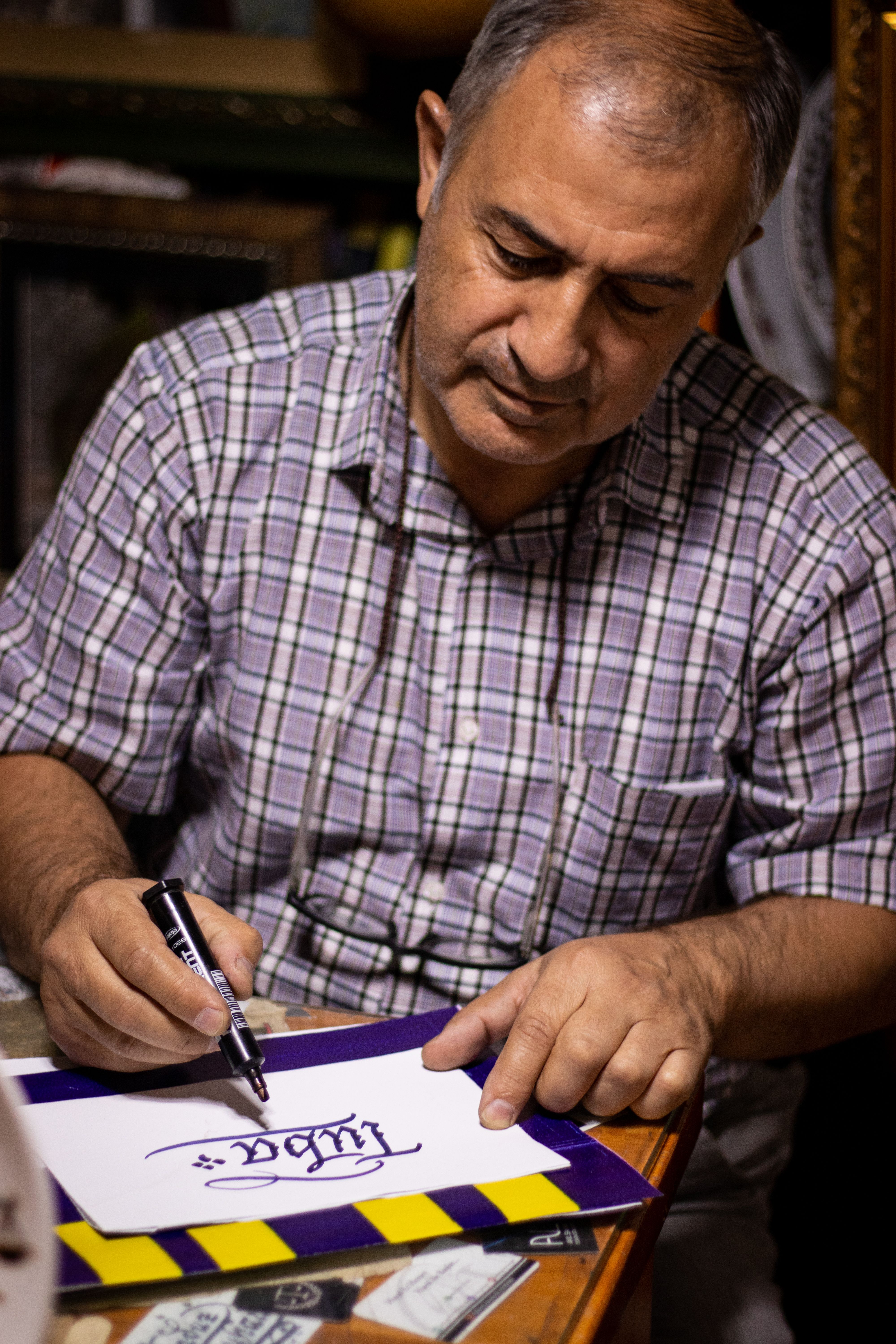 Middle-aged man practicing calligraphy with a marker in an indoor setting.