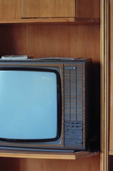 Retro television set displayed on a wooden shelf, showcasing nostalgic electronics.