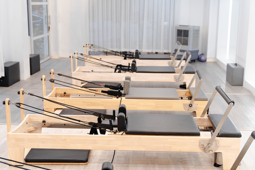Bright, minimalist Pilates studio featuring several reformer machines ready for fitness enthusiasts.