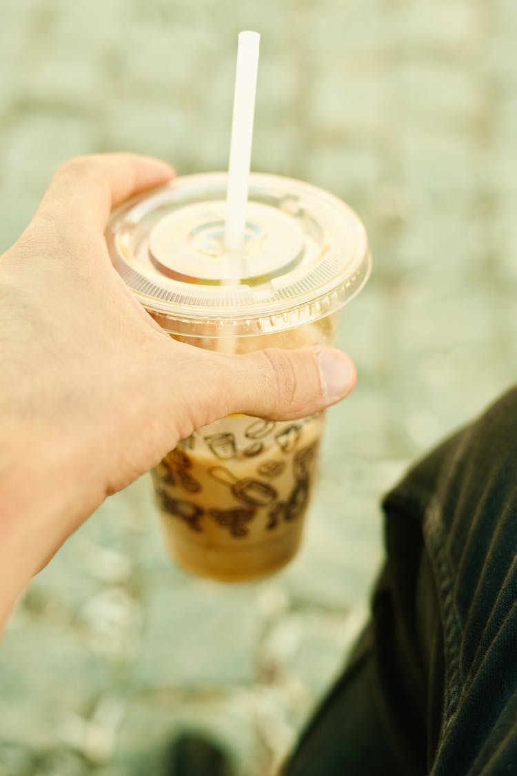 Person Holding A Drink In A Plastic Cup With A Straw