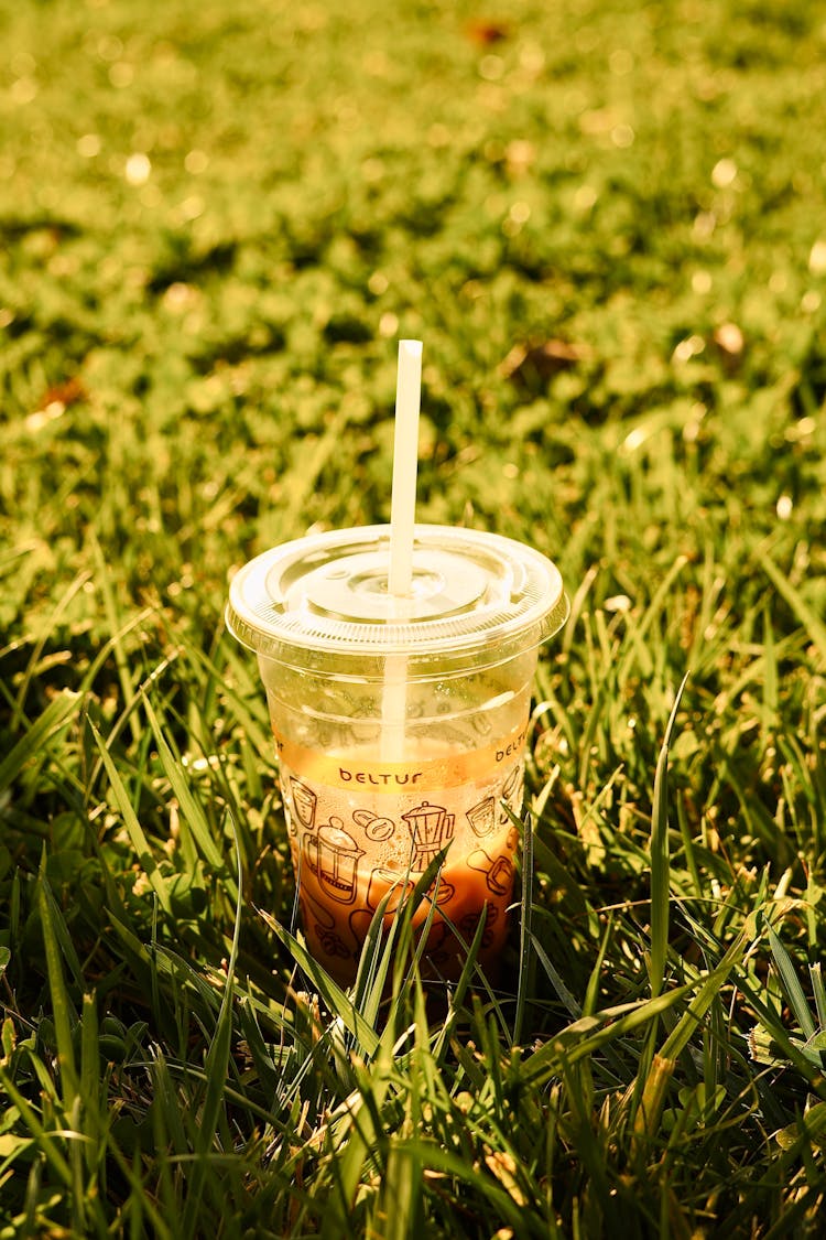 A Drink In A Plastic Cup With A Straw Standing On The Ground