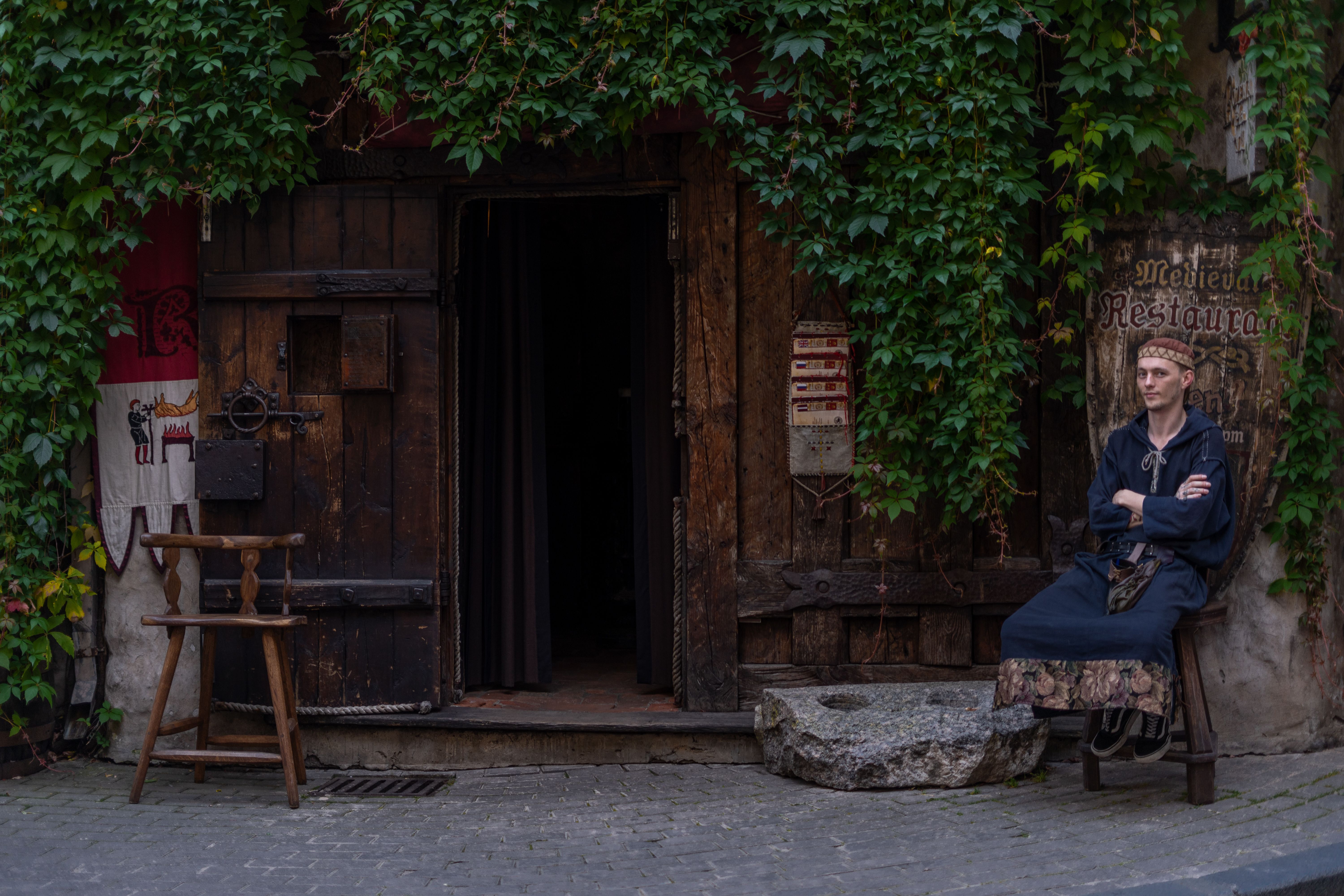 Man in traditional attire outside a medieval restaurant in Riga, Latvia.