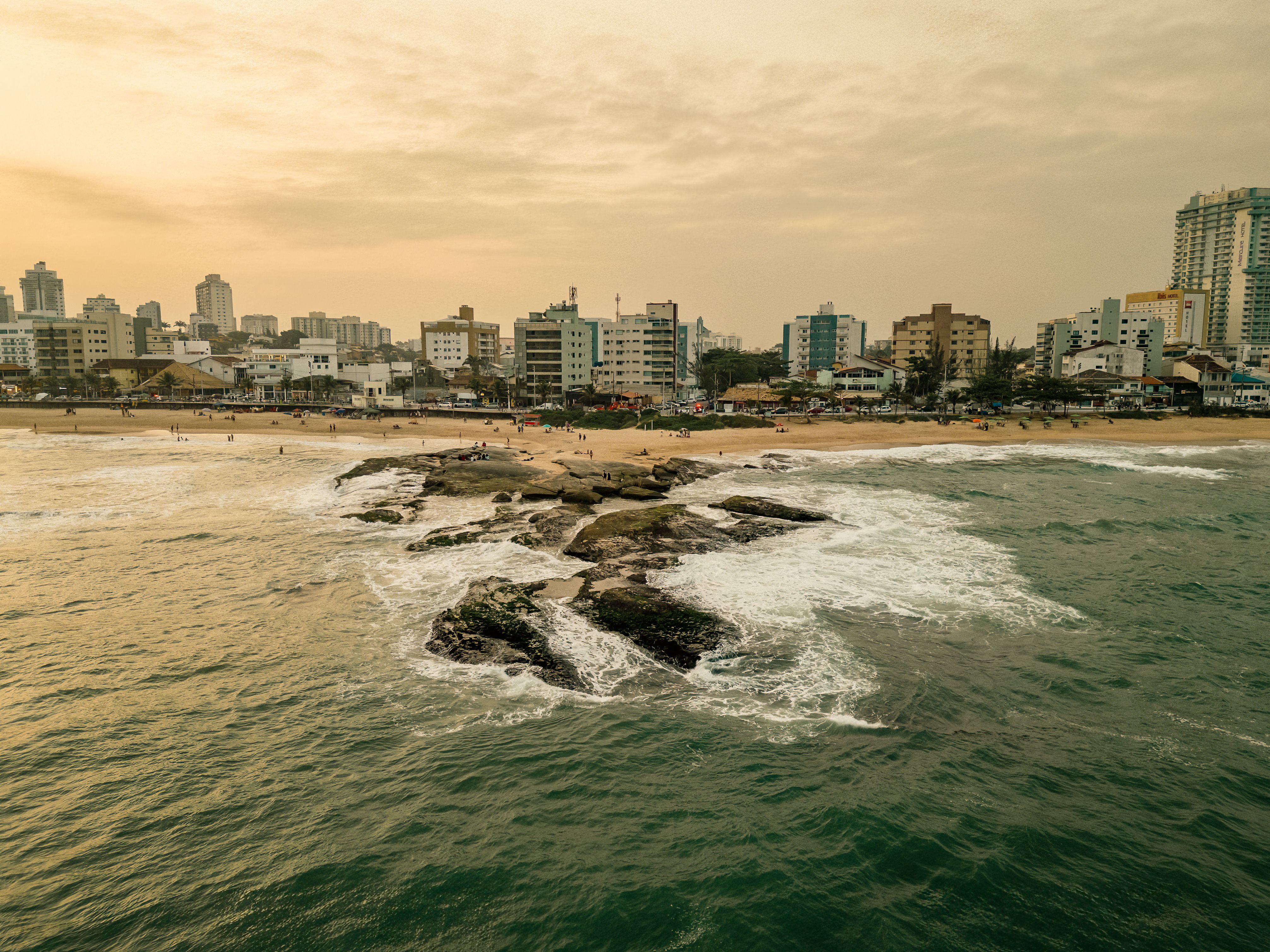 Stunning aerial view of Cavaleiros Beach in RJ, Brazil, during sunset with waves hitting the shore.