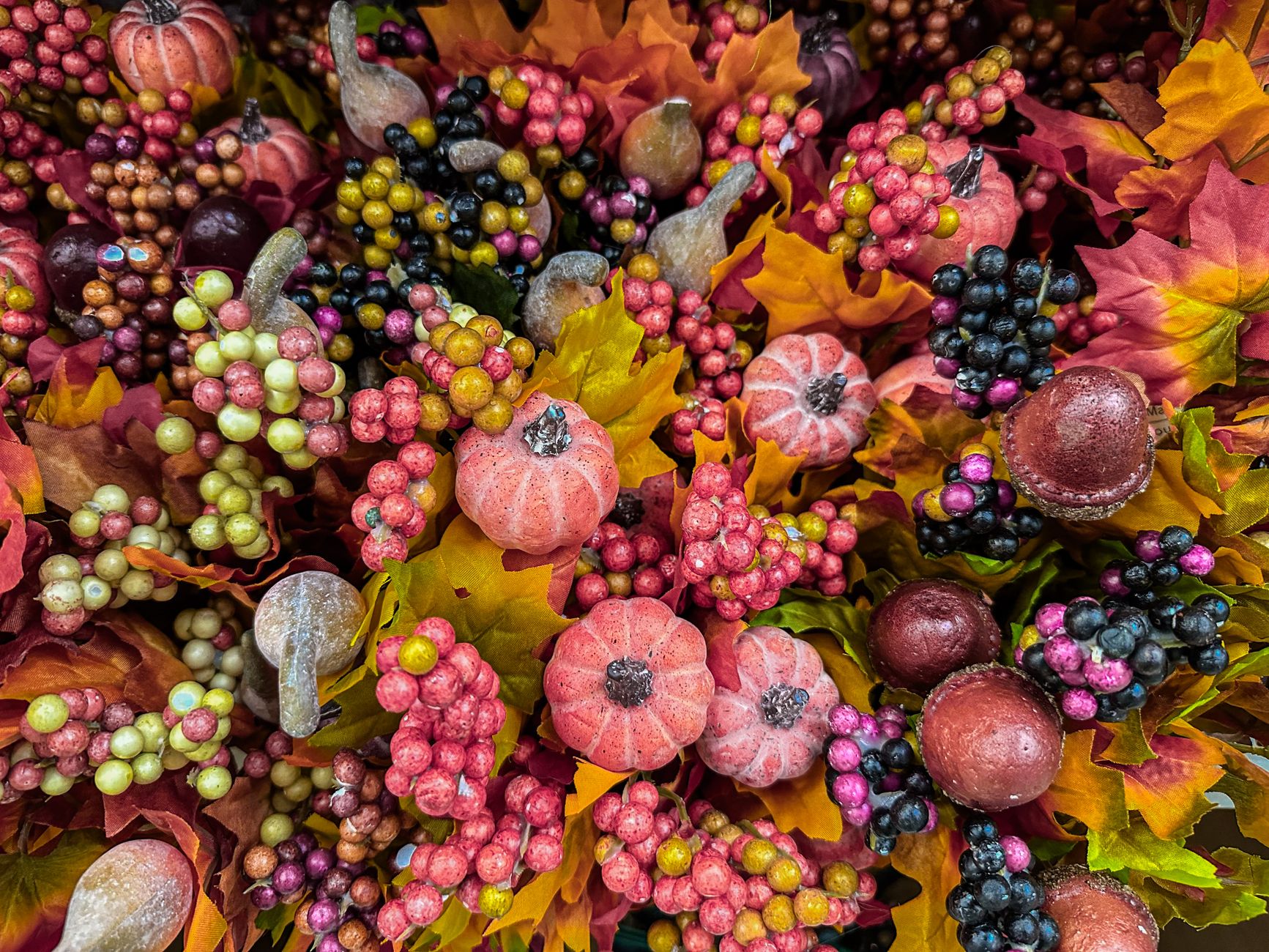 Warm apple cider donuts arranged in a paper bag next to autumn leaves and a cinnamon stick