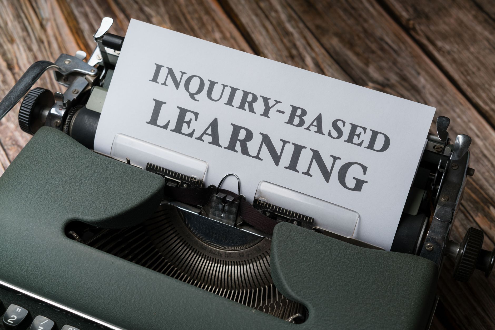 Close-up of a typewriter with paper showing 'INQUIRY-BASED LEARNING'.