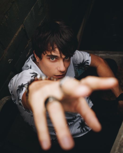 Portrait of a young man reaching forward in a dramatic urban setting. Captured from above for a dynamic effect.