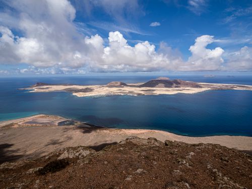 Free A breathtaking view of the Canary Islands coastline with clear blue waters and dramatic clouds. Stock Photo