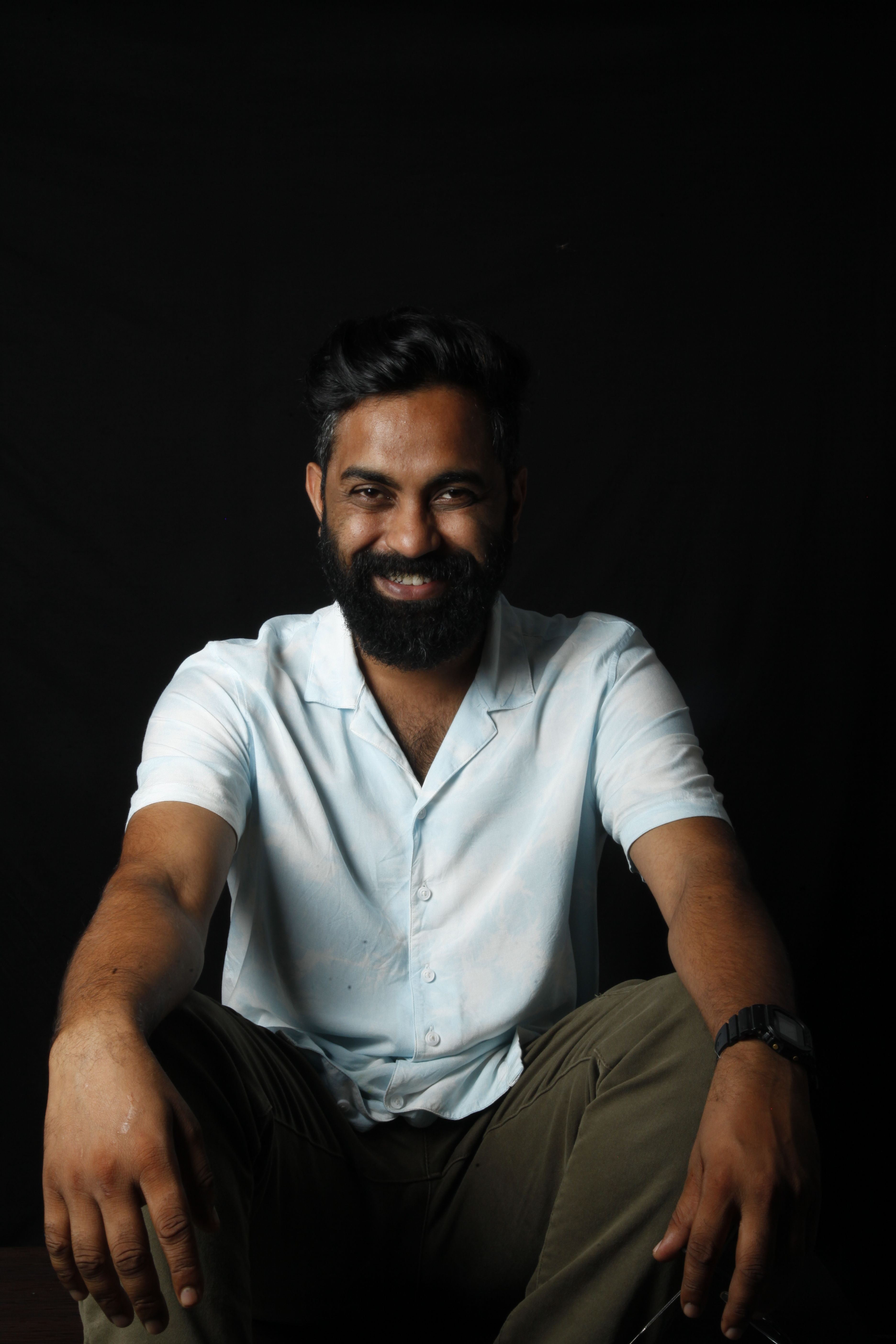 Portrait of a bearded man posing confidently in a studio with dark background.