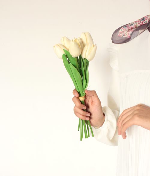 Free Elegant bouquet of white tulips held by a woman against a minimal background. Stock Photo