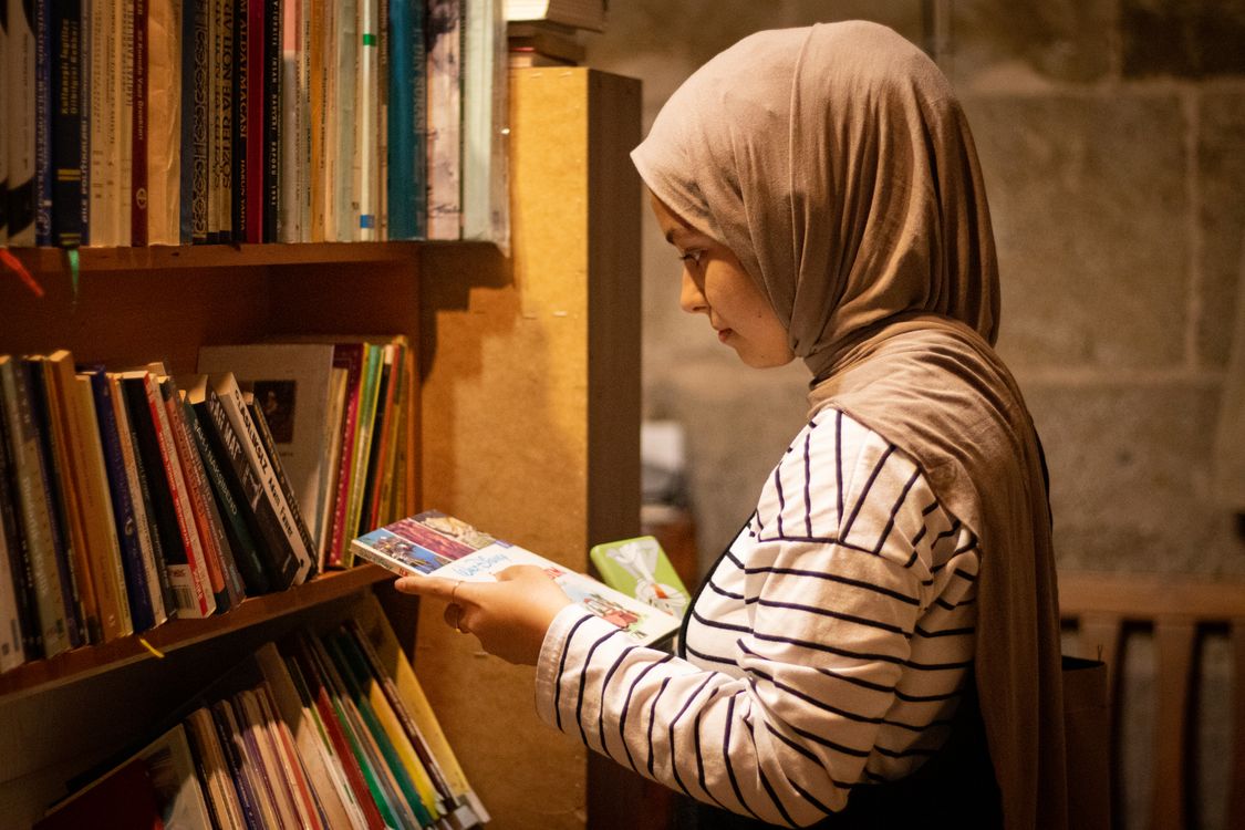 Side View of a Young Woman in a Hijab Holding a Book in a Library ...