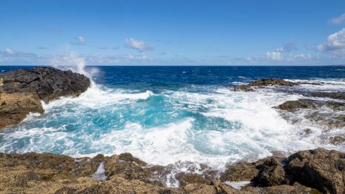 Free Vibrant ocean waves crash against a rocky coastline under a clear blue sky. Stock Photo