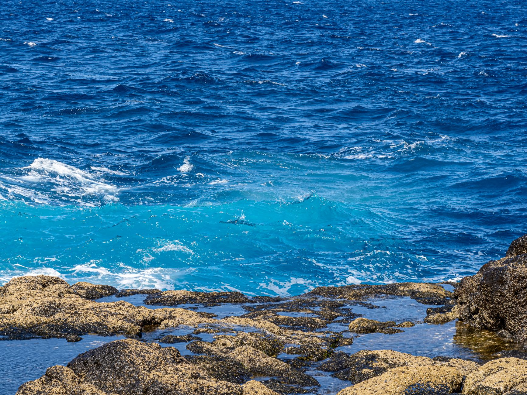 A stunning view of a rocky shoreline with vibrant blue waves crashing onto the coast.. pexels, stunning, view