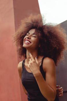 一幅充满活力的肖像画中，一位微笑的女子留着自然的非洲裔发型，背景色彩斑斓