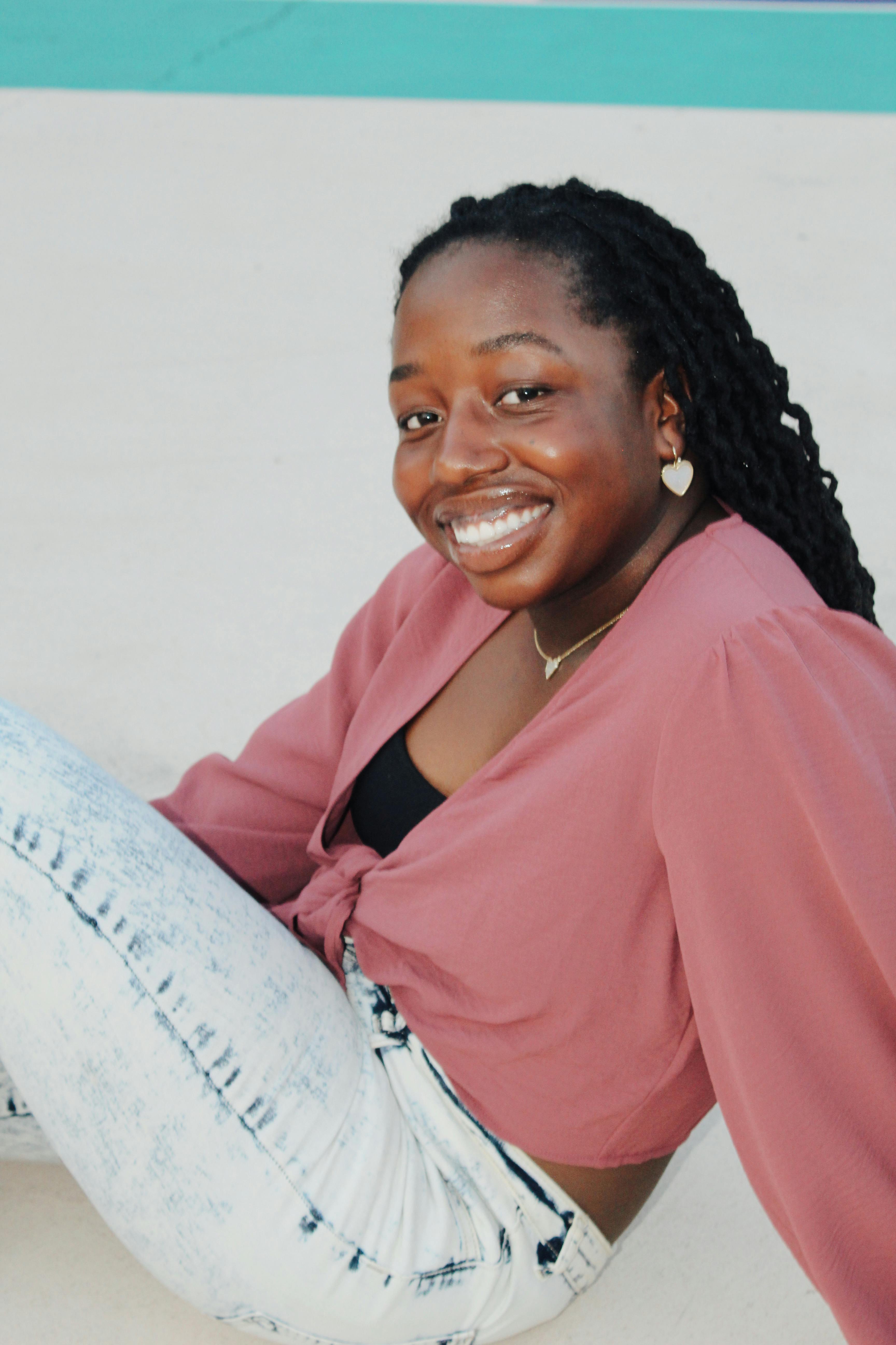 Smiling Woman in a Pink Blouse and Light Wash Jeans · Free Stock Photo