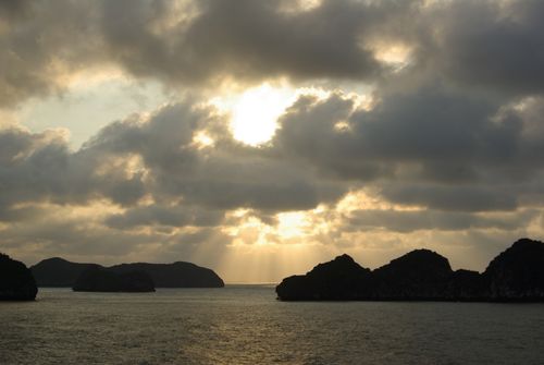 Free Serene coastal landscape with dramatic sunset and clouds casting sunbeams over the sea. Stock Photo