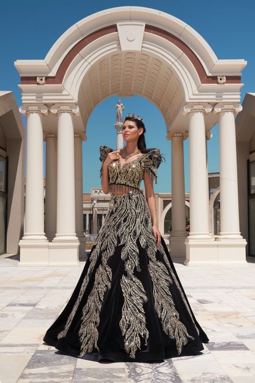 Free A model in an ornate gown stands elegantly within a colonnade, showcasing fashion and architecture. Stock Photo