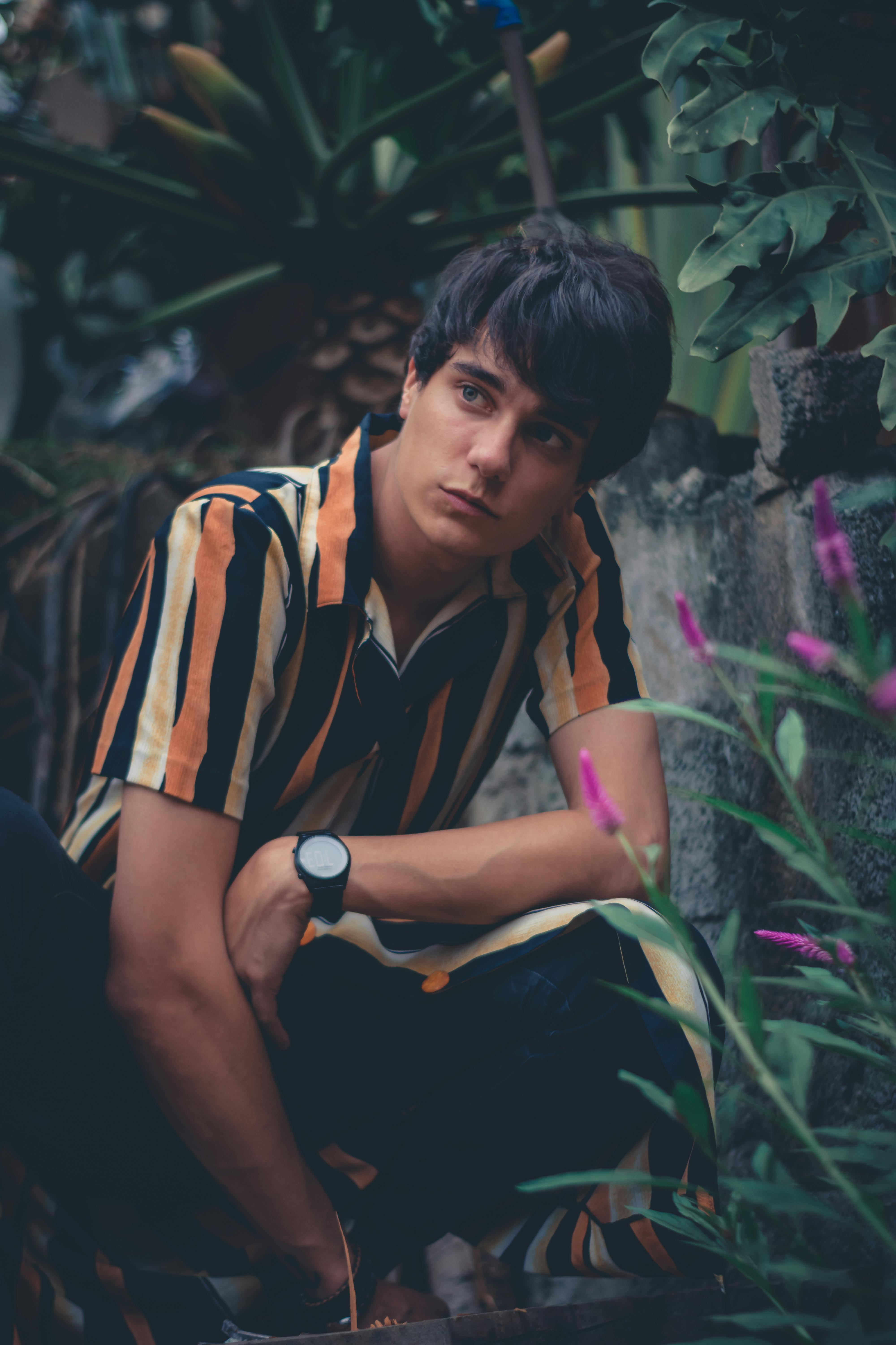 穿着条纹时装的年轻人在郁郁葱葱的绿植中摆出户外姿势