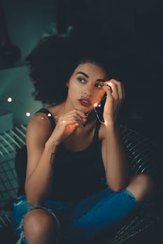 一位卷发女子手握灯串，在忧郁氛围中展现时尚肖像