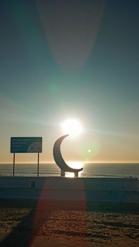 Captivating sunset over the sea with a crescent sculpture at Mar del Plata, Argentina.
